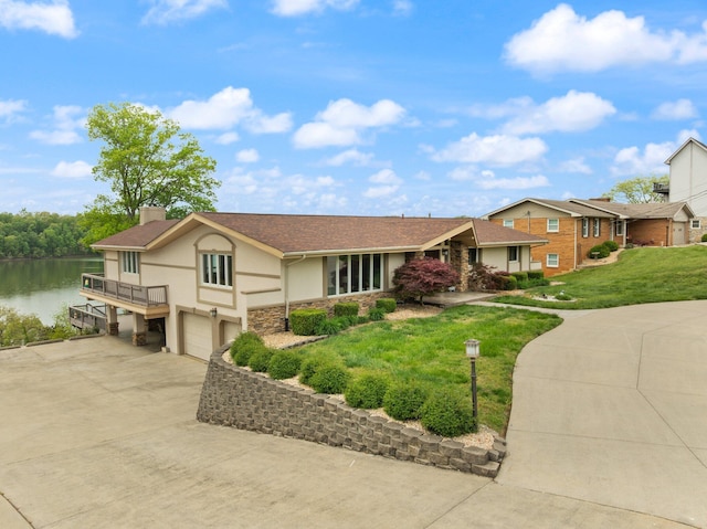 view of front facade featuring stone siding, stucco siding, a chimney, an attached garage, and a water view