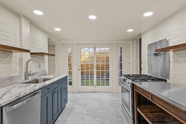 kitchen featuring open shelves, light stone countertops, a sink, and appliances with stainless steel finishes