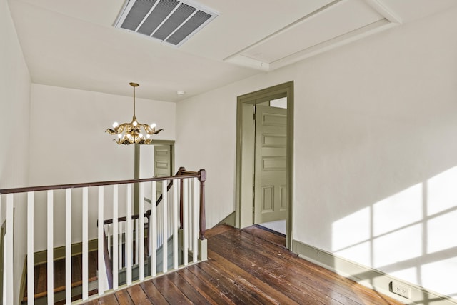 hallway featuring dark wood finished floors, a chandelier, an upstairs landing, and visible vents