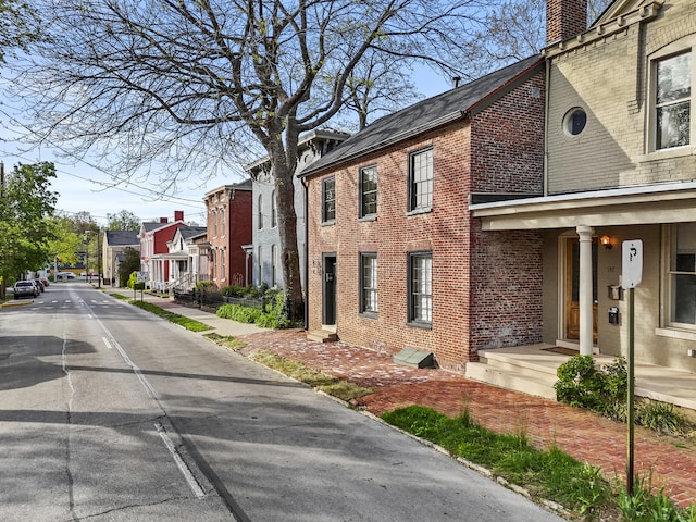 view of property exterior featuring a chimney, brick siding, and a residential view