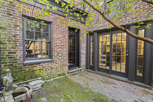 doorway to property featuring brick siding and a patio area