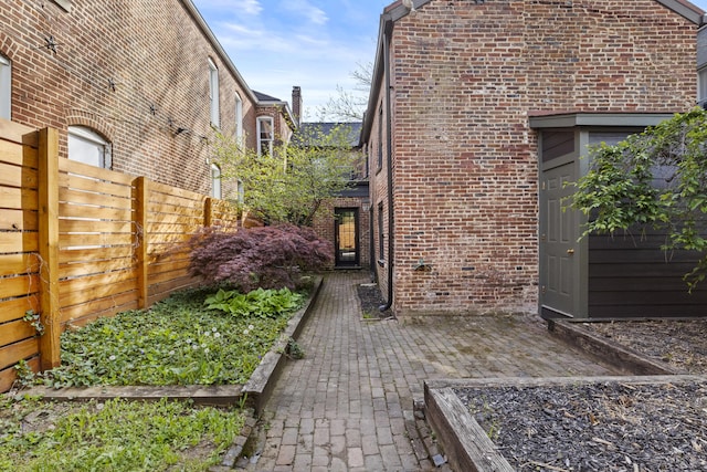view of side of home with brick siding, fence, and a patio