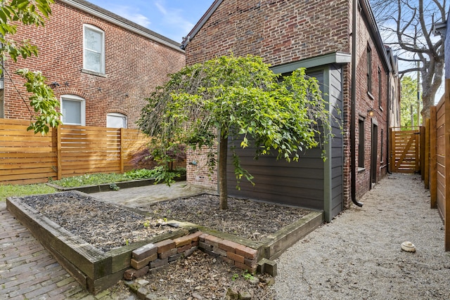 back of house with a fenced backyard and brick siding