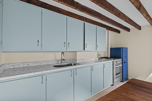 kitchen with stainless steel range with gas stovetop, light wood-style flooring, beam ceiling, a sink, and blue cabinetry