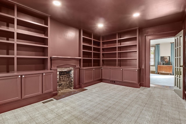 unfurnished living room featuring carpet floors, built in features, a stone fireplace, and recessed lighting