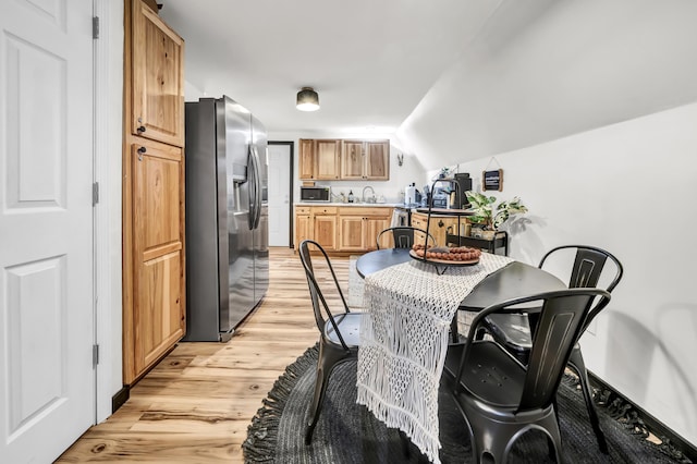 dining space featuring light wood finished floors and vaulted ceiling