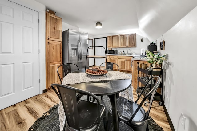 dining room with baseboards, light wood-type flooring, and vaulted ceiling