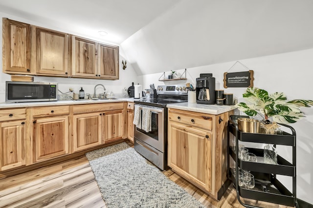 kitchen with light countertops, a sink, stainless steel appliances, and light wood-style floors