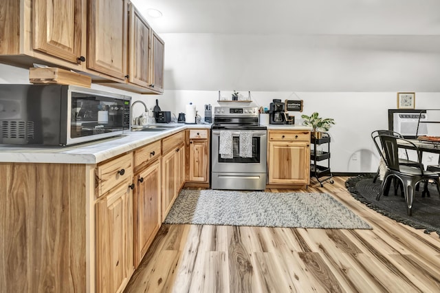 kitchen with electric stove, light wood-type flooring, light countertops, and a sink