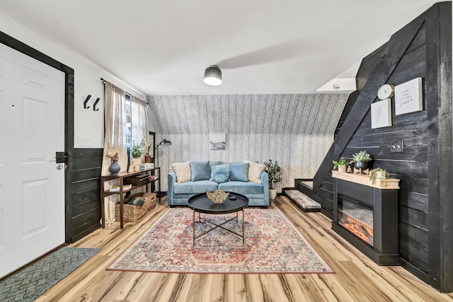 living room with an accent wall, wood finished floors, and a glass covered fireplace