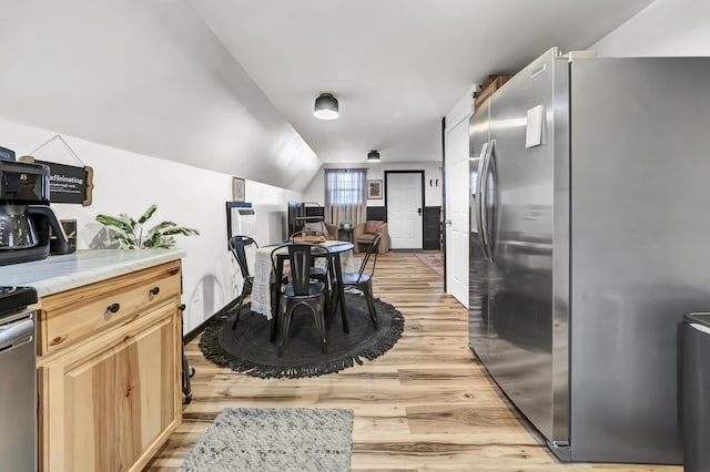kitchen featuring stainless steel refrigerator with ice dispenser, light brown cabinets, light countertops, and light wood-style flooring