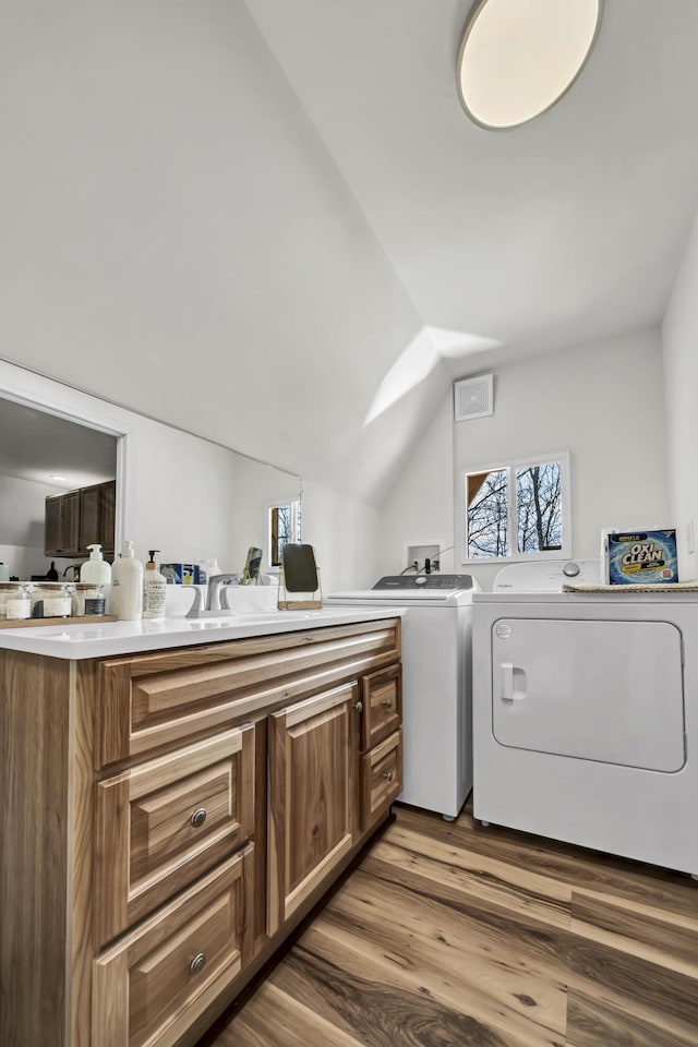 washroom with wood finished floors, independent washer and dryer, laundry area, and a sink