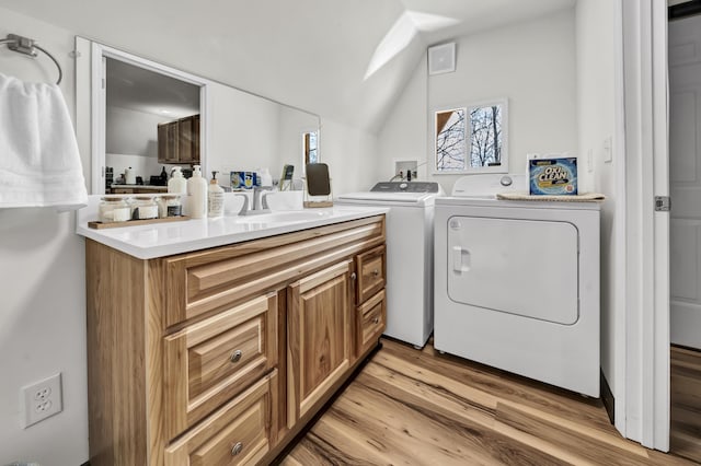 laundry area featuring a sink, washing machine and clothes dryer, laundry area, and light wood-type flooring