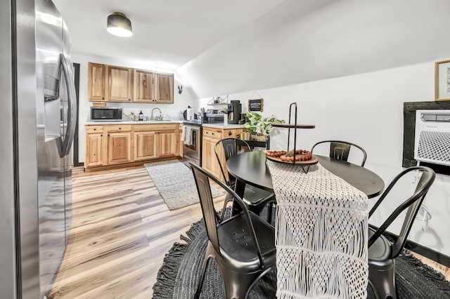 dining space featuring light wood-style floors and vaulted ceiling