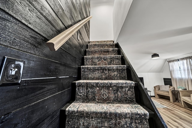 stairway with wood finished floors and vaulted ceiling