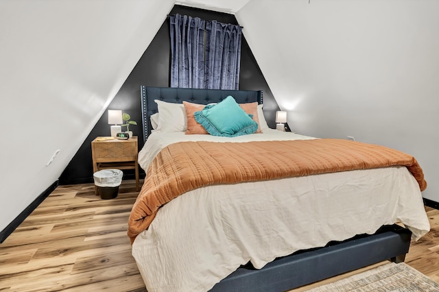 bedroom featuring wood finished floors, vaulted ceiling, and baseboards