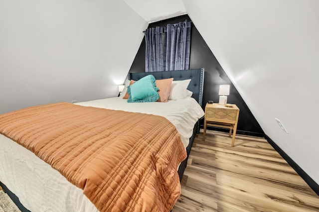 bedroom with wood finished floors and vaulted ceiling