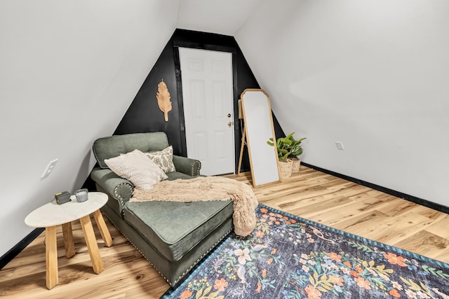 living area featuring lofted ceiling, wood finished floors, and baseboards