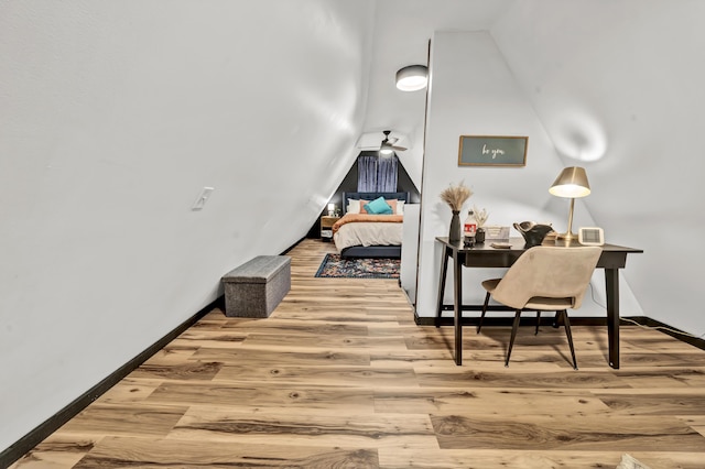 interior space with baseboards, wood finished floors, and lofted ceiling