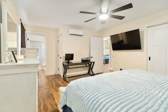 bedroom featuring a wall mounted air conditioner, ensuite bathroom, ceiling fan, light wood finished floors, and baseboards