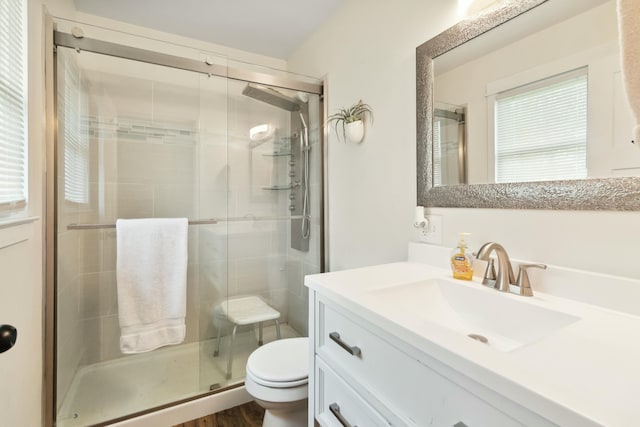full bath with wood finished floors, vanity, a shower stall, and toilet