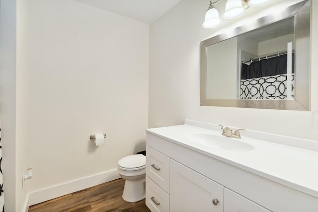 full bathroom featuring baseboards, wood finished floors, vanity, and toilet