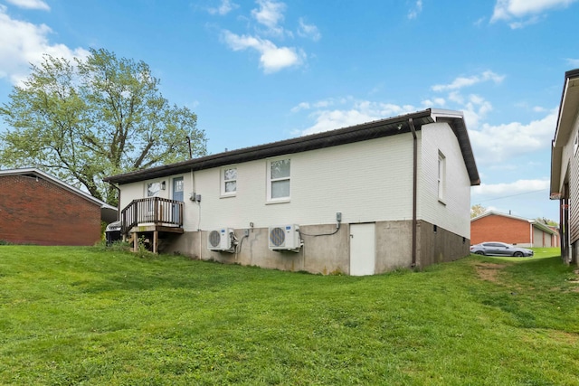 rear view of property featuring a lawn and ac unit