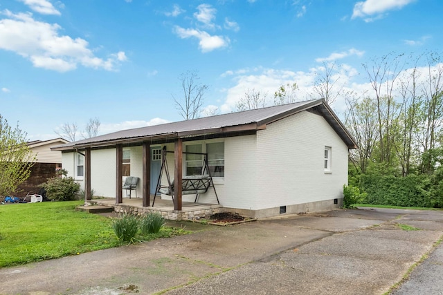 view of front of property with brick siding, a porch, a front yard, and metal roof