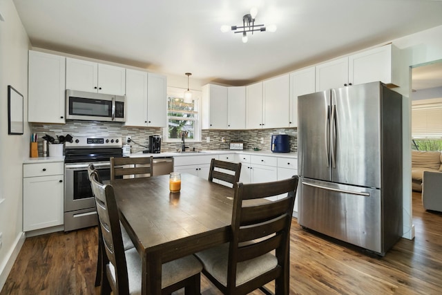 kitchen with appliances with stainless steel finishes, tasteful backsplash, a sink, and dark wood-style floors