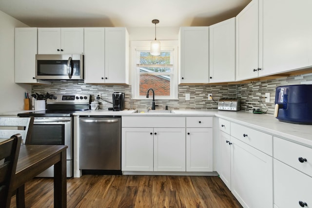 kitchen with white cabinets, dark wood-style flooring, stainless steel appliances, and a sink