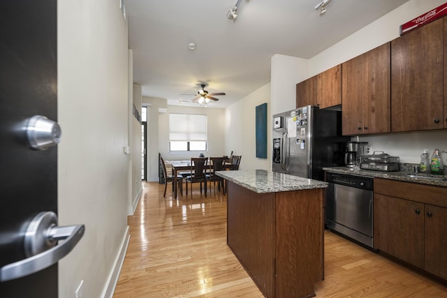 650 S Mill St Unit 219, Lexington, KY 40508 - kitchen with stone countertops, a ceiling fan, a kitchen island, light wood-style flooring, and appliances with stainless steel finishes