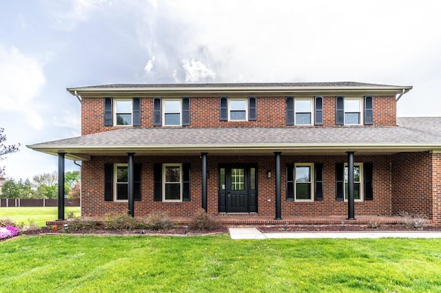 view of front of house featuring a porch, a shingled roof, and a front yard