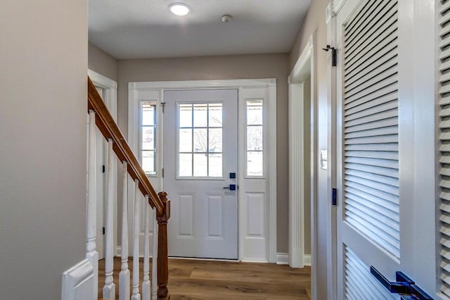entrance foyer with baseboards, wood finished floors, and stairway