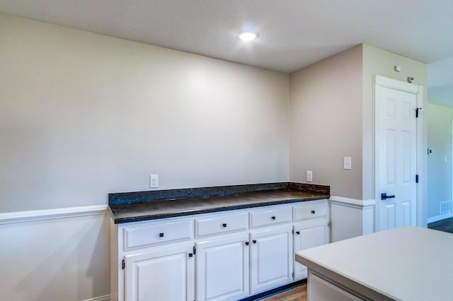 kitchen with recessed lighting, dark countertops, baseboards, and white cabinetry