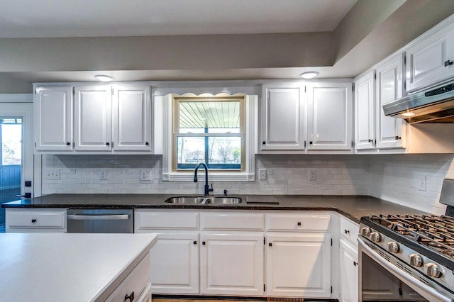 kitchen with dark countertops, white cabinetry, stainless steel appliances, and a sink