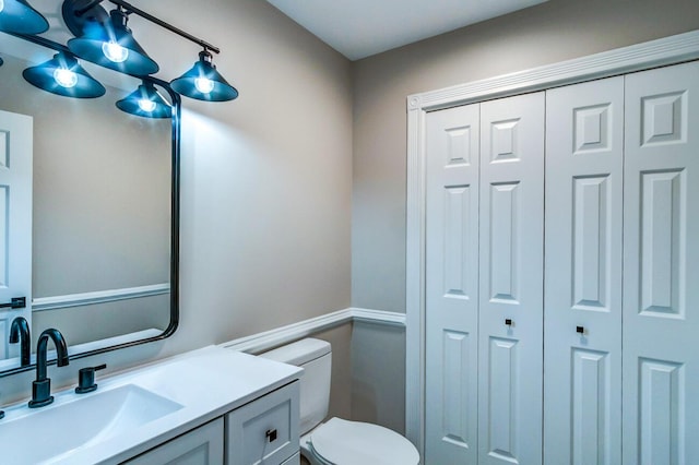 bathroom with toilet, vanity, and a closet