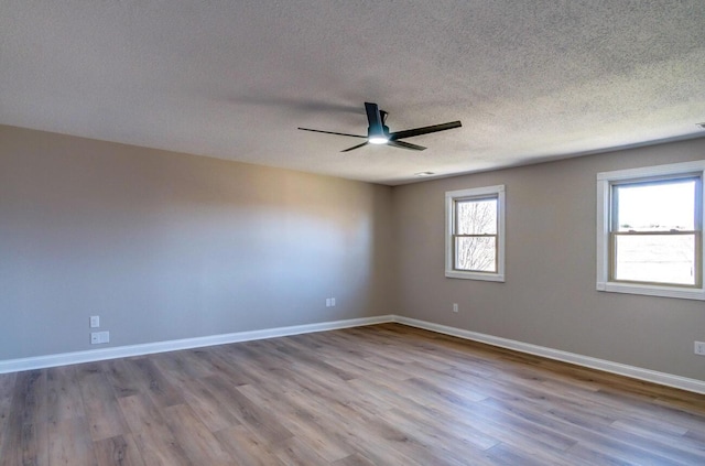 empty room featuring baseboards, wood finished floors, a textured ceiling, and ceiling fan