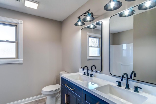 bathroom featuring double vanity, toilet, baseboards, and a sink