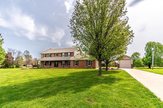 view of front of property with an outbuilding, brick siding, a front yard, and a detached garage