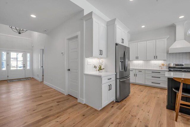 4137 Meadowlark Rd, Lexington, KY 40509 - kitchen with light countertops, premium range hood, light wood-style floors, appliances with stainless steel finishes, and white cabinetry