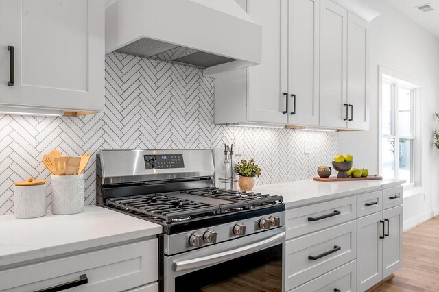 4137 Meadowlark Rd, Lexington, KY 40509 - kitchen featuring stainless steel range with gas cooktop, visible vents, custom exhaust hood, white cabinetry, and decorative backsplash