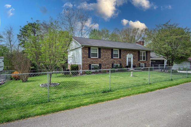 bi-level home featuring a front lawn, a chimney, brick siding, a garage, and fence private yard