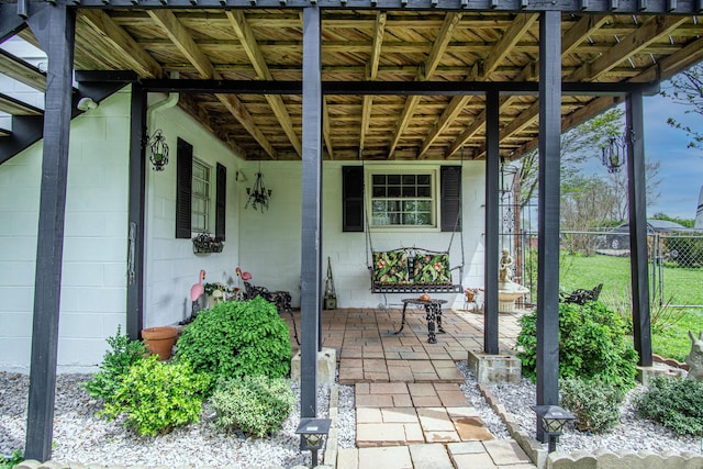 view of patio featuring fence and a porch