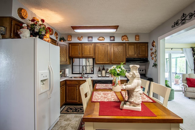 kitchen featuring brown cabinets, under cabinet range hood, light countertops, a sink, and white refrigerator with ice dispenser