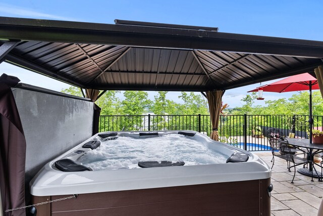 deck with a hot tub, a gazebo, a patio area, and fence