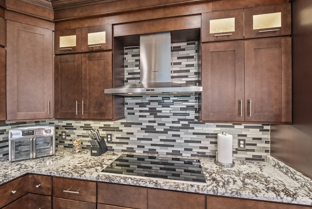 kitchen with wall chimney exhaust hood, black electric stovetop, backsplash, and glass insert cabinets