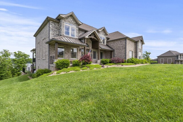 craftsman inspired home with a standing seam roof, a front lawn, and brick siding