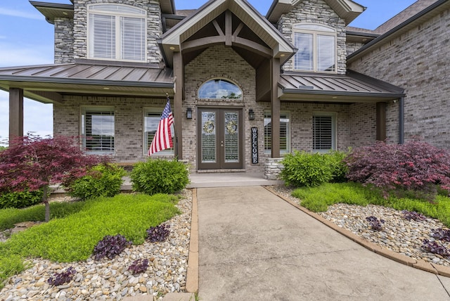 view of exterior entry featuring a standing seam roof, brick siding, french doors, metal roof, and a porch