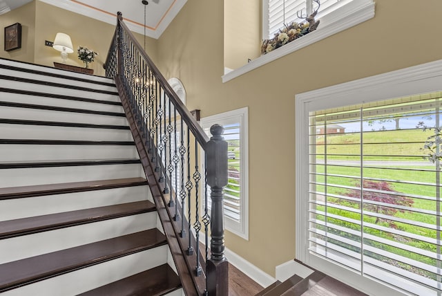 staircase with baseboards, wood finished floors, and ornamental molding