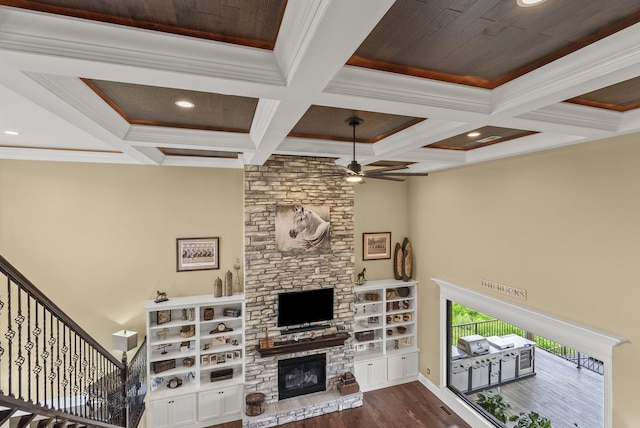 living area with a fireplace, ceiling fan, wood finished floors, ornamental molding, and beamed ceiling